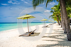 Tropical beach background at Panglao Bohol island with Beach chairs on the white sand beach with blue sky and palm trees