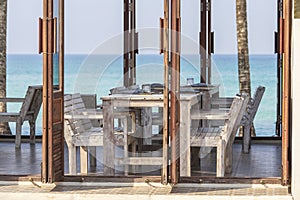 Tropical beach cafe with wooden table and chairs against the backdrop of the blue sea, Thailand. Travel concept