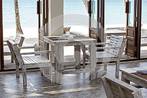 Tropical beach cafe with wooden table and chairs against the backdrop of the blue sea, Thailand. Travel concept