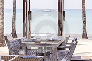 Tropical beach cafe with wooden table and chairs against the backdrop of the blue sea, Thailand. Travel concept