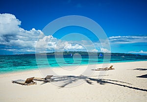 Tropical beach with chaise longues