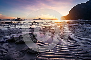 Tropical beach in ebb time low tide on sunset. Mudflats and sun reflections at the golden hour. mountain chain isles at