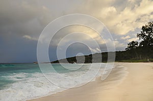 Tropical beach with granite rocks and cloudy stormy sky.