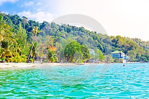 Tropical beach with green palm trees and bungalows, summer sea vacation, Koh Chang island in Thailand