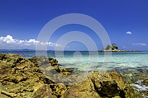 Tropical beach at Kapas Island, Malaysia. Wet Rock and crystal clear sea water with blue sky background