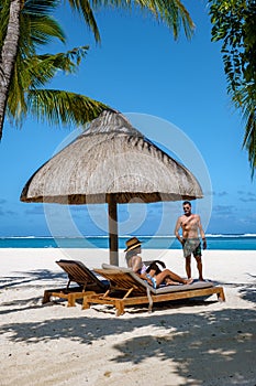 Tropical beach with palm trees and white sand blue ocean and beach beds with umbrella,Sun chairs and parasol under a