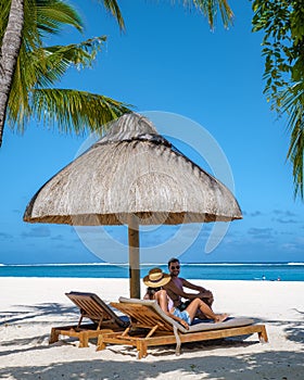 Tropical beach with palm trees and white sand blue ocean and beach beds with umbrella,Sun chairs and parasol under a