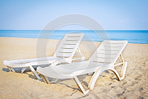 Tropical beach with sand and blue sea at resort. Sun beds on sea beach. Summer vacation.