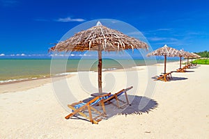 Tropical beach scenery with parasol and deck chairs