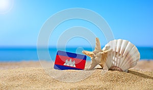 Tropical beach with seashells and Cambodia flag.