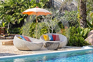 Tropical beach with swimming pool, coconuts palm trees, rattan daybeds and umbrella near sea, Thailand