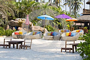 Tropical beach with swimming pool, coconuts palm trees, rattan daybeds and umbrella near sea, Thailand