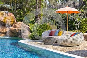 Tropical beach with swimming pool, coconuts palm trees, rattan daybeds and umbrella near sea, Thailand