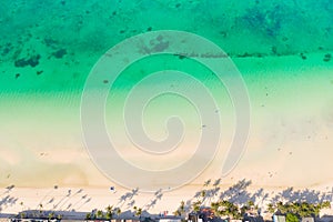 Tropical beach with white sand and palm trees, view from above. Turquoise lagoon with a sandy bottom.