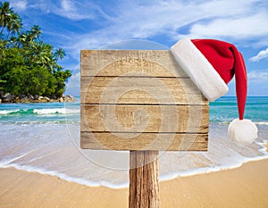 Tropical beach wooden signboard with Christmas hat