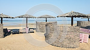 Tropical beach with wooden umbrellas, sun beds and wind screens, color toning applied