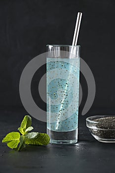 Tropical blue cocktail with chia seeds in glass on black background. Close up. Vertical. Detox and freshness.