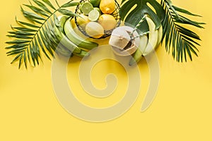 Tropical border of fruits, banana, lime, leaves palms on punchy yellow background. Space for text. Detox tour