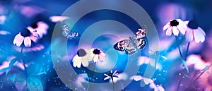 Tropical butterflies and pink bright summer flowers on a background of blue foliage in a fairy garden. Macro artistic image.