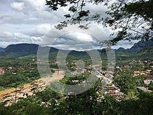 Tropical city in Laos, South East Asia that is divided by a large brown colored river seen from a distance