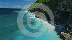 Tropical coastline with rocks and blue ocean with waves in Bali. Aerial view