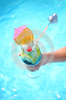 Tropical cocktail in a childrens hand in front of