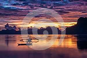 Tropical colorful sunset with a banca boat in El Nido