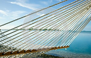 Tropical colours through White string hammock strung between coconut palms on idyllic tropical island beach