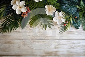 Tropical flowers and palm leaves on wooden background