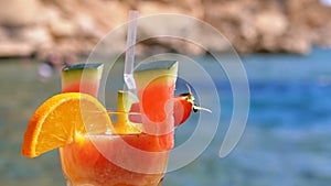 Tropical Fresh Cocktail in a Glass with Straw on the Beach of Egypt Stands on a Rock on Background of the Red Sea