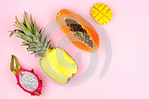 Tropical fruit flat lay on a pastel pink background. Corner orientation.