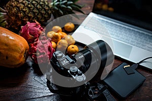 Tropical fruit near modern laptop on wooden background. Vegan lifestyle.