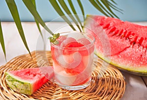 Tropical fruit salad with melon and watermelon balls in glass under the palm leaf