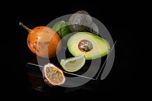 Tropical fruits: avocado, lemon, lime, granadilla, passion fruit on a dark background