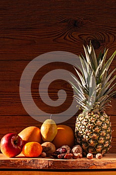 Tropical fruits and nuts vegan diet. Pineapple, grapefruit, orange, pear, walnuts on wooden background,weight loss foods