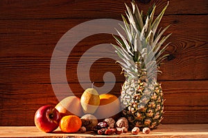 Tropical fruits and nuts vegan diet. Pineapple, grapefruit, orange, pear, walnuts on wooden background,weight loss foods