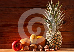 Tropical fruits and nuts vegan diet. Pineapple, grapefruit, orange, pear, walnuts on wooden background,weight loss foods