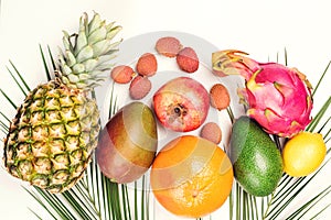 Tropical fruits, palm leaves on white background. Healthy lifestyle and summer concept. Flat lay, top view. Pineapple, lychee,
