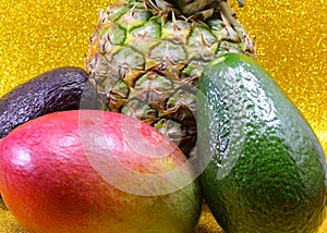 Tropical fruits paradise with pineapple avocado and mango on golden glitter background for healthy eating concept