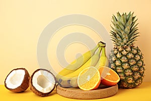 Tropical fruits. Pineapple, coconut, orange and banana on beige background