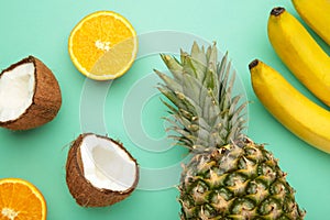 Tropical fruits. Pineapple, coconut, orange and banana on mint background
