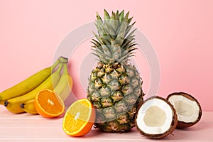 Tropical fruits. Pineapple, coconut, orange and banana on pink background