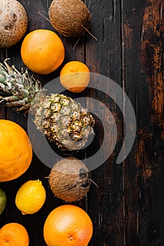 Tropical fruits, pineapple, mango and oranges, on old dark  wooden table background, top view flat lay, with copy space for text