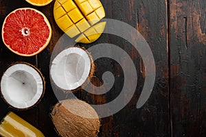 Tropical fruits, pineapple, mango and oranges, on old dark  wooden table background, top view flat lay, with copy space for text