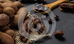 Tropical fruits, Tamarindo beans in shell on a brown butchers block on a dark background, healthy fruit. banner, menu, recipe