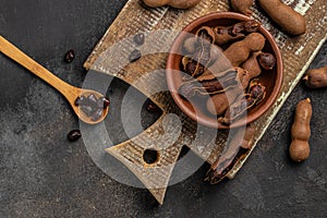 Tropical fruits, Tamarindo beans in shell on a brown butchers block on a dark background, healthy fruit. banner, menu, recipe