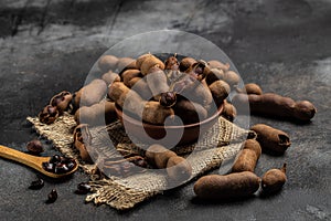 Tropical fruits, Tamarindo beans in shell on a brown butchers block on a dark background, healthy fruit. banner, menu, recipe