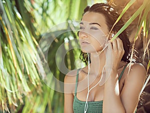 Tropical girl listening to music on earphones