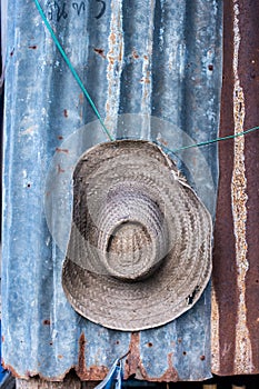 Tropical hat hanging on a rust zinc wall in a hut farm in Asia