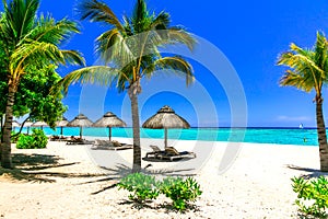 Tropical holidays - beach chairs and umbrellas in Mauritius island.